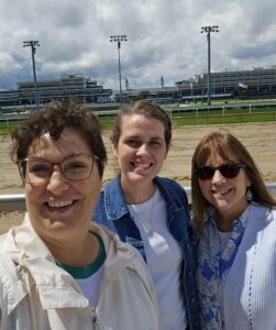 Three women with racetrack behind them